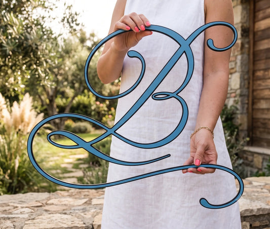 Woman holding a large cursive wood monogram letter "B" outdoors, showing true scale