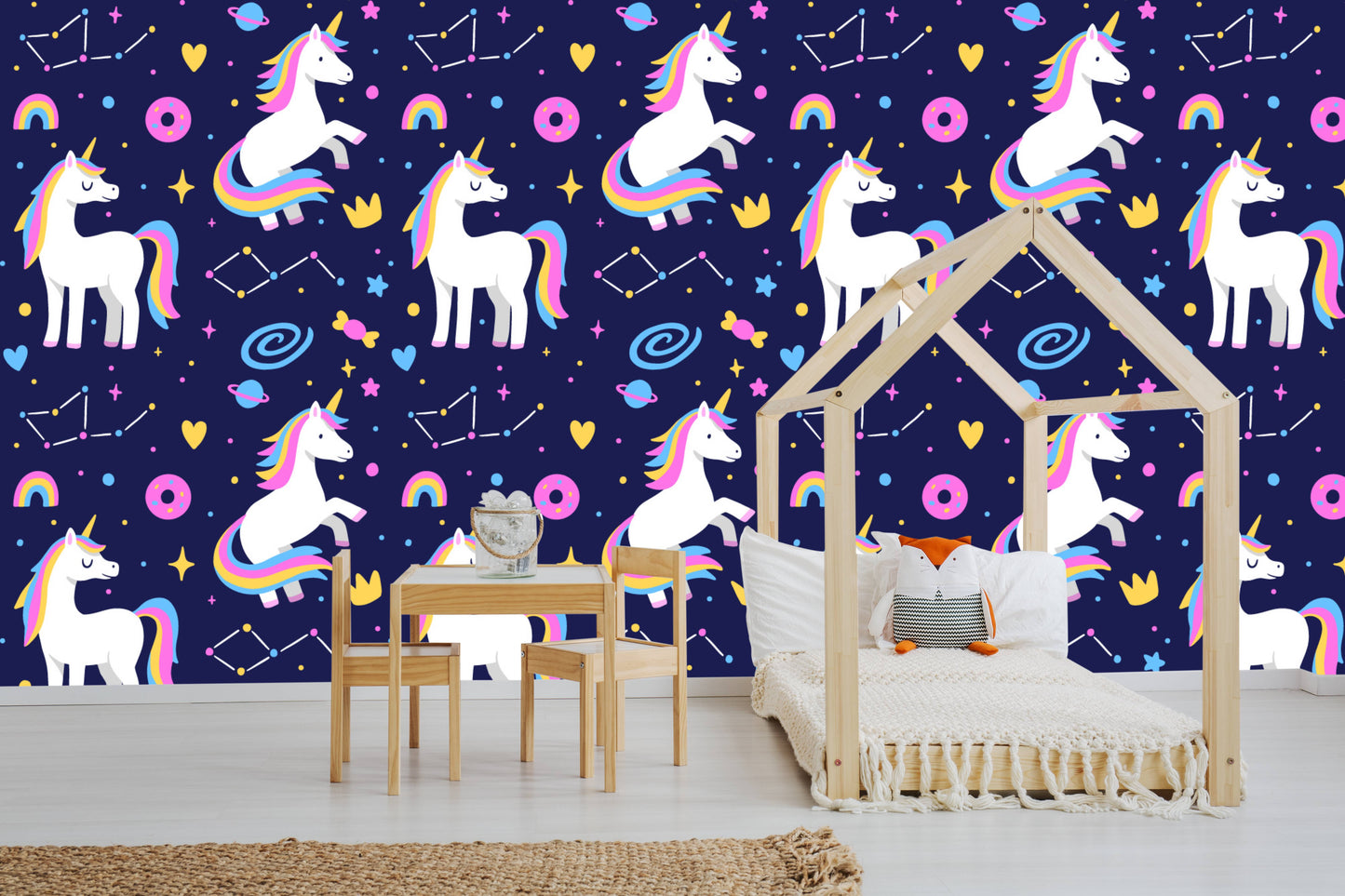 Galaxy unicorns wallpaper behind a wooden play table and chairs in a kids room