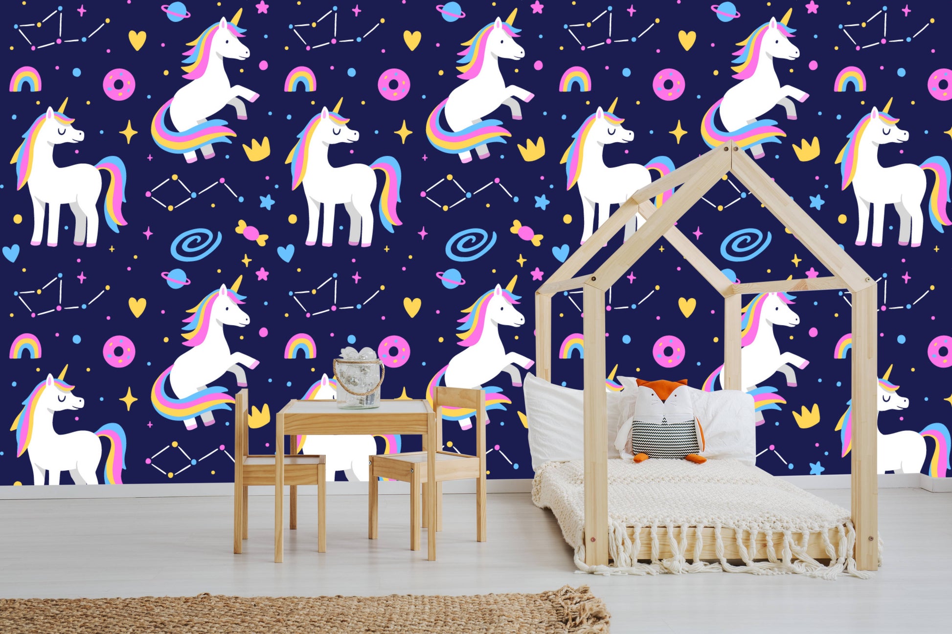 Galaxy unicorns wallpaper behind a wooden play table and chairs in a kids room