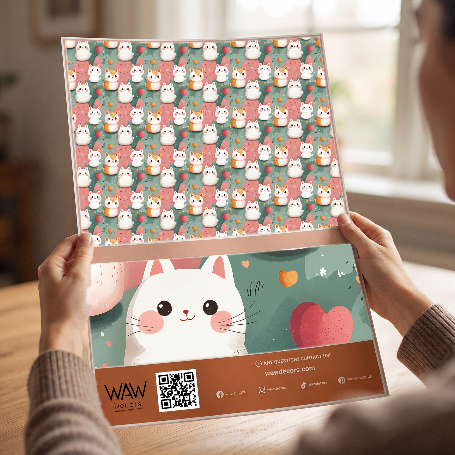 Close-up of a rolled kawaii kittens peel and stick wallpaper panel being applied to a wall
