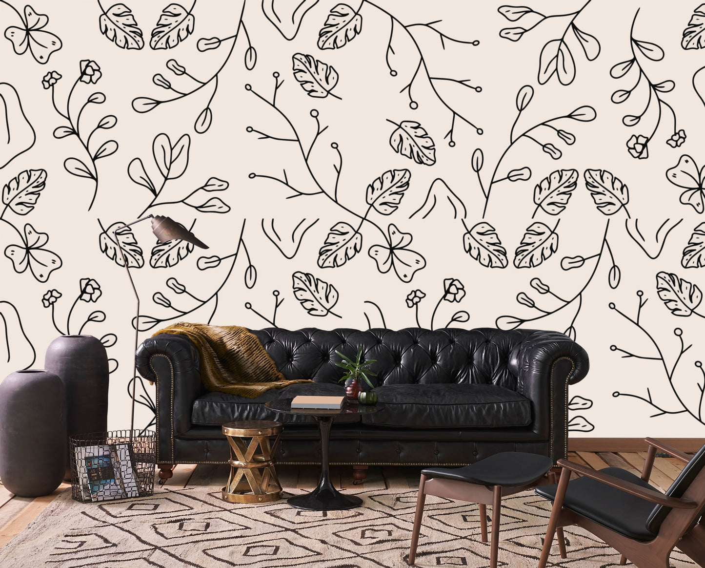 Minimal botanical line art wallpaper behind a black leather chesterfield sofa in a living room