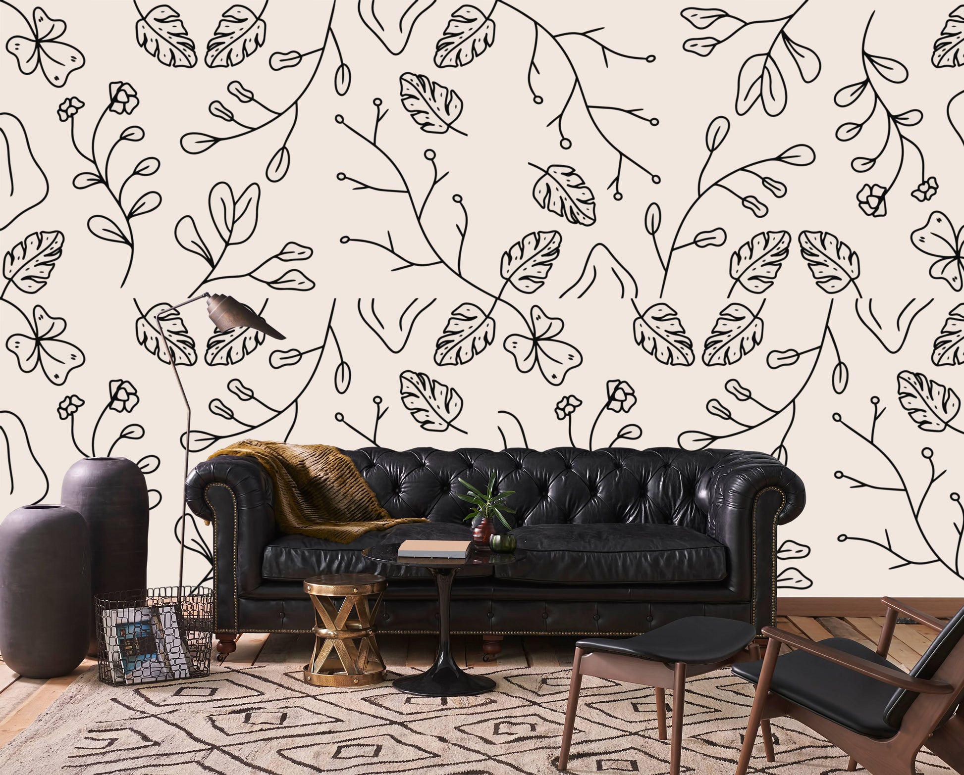 Minimal botanical line art wallpaper behind a black leather chesterfield sofa in a living room