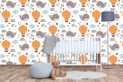 Hello World whale nursery wallpaper behind a white crib with a knit pouf and teddy bear